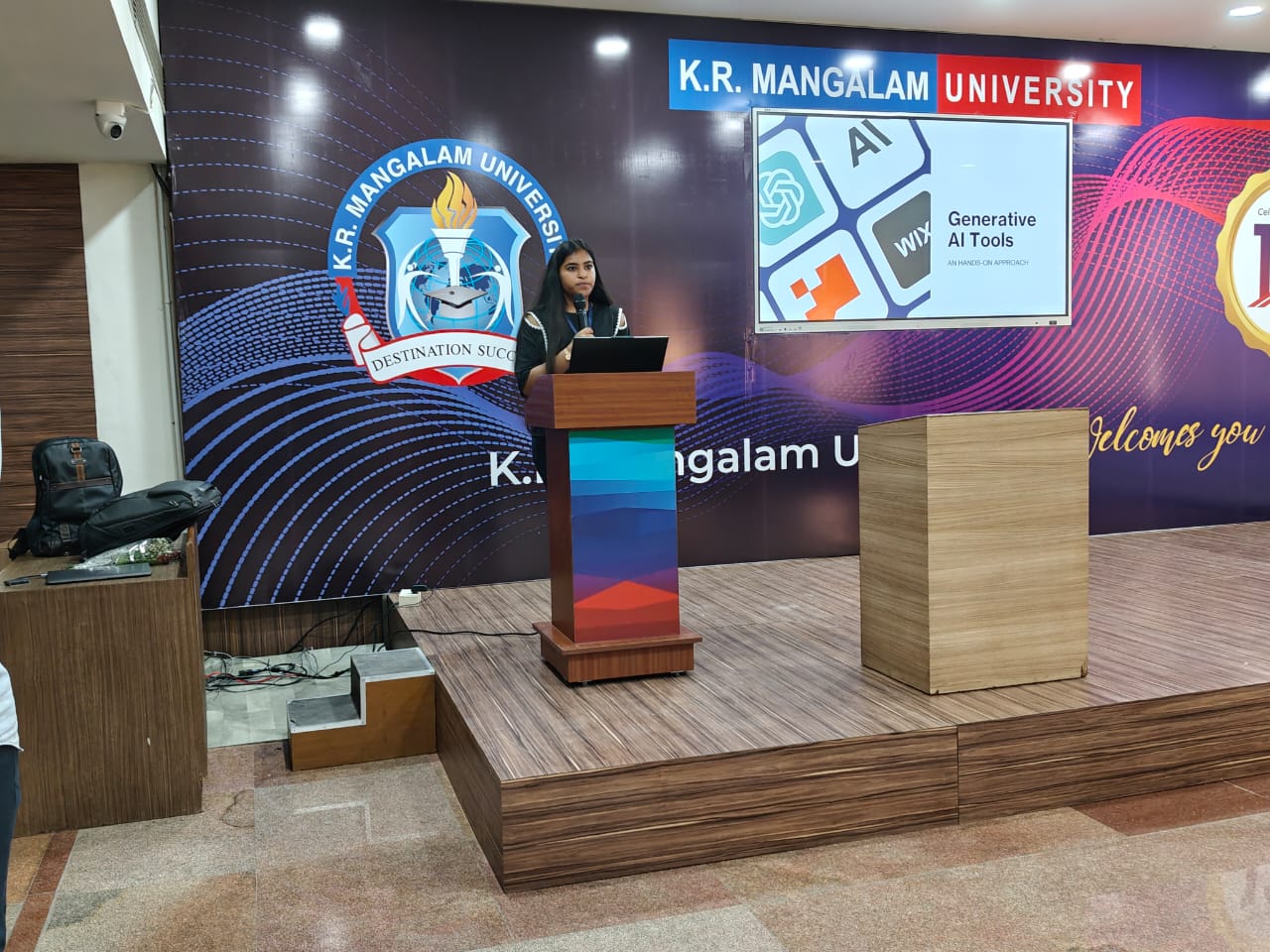 A speaker at the podium introducing the Generative AI Tools hands-on workshop at K.R. Mangalam University